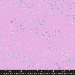 May include: A light purple fabric with a speckled pattern of white, light blue, and dark blue dots. The fabric has a ruler along the bottom with the text "RUBY STAR SOCIETY".
