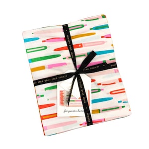 Könnte beinhalten: Ein Bündel Stoffquadrate mit einem farbenfrohen Stiftdesign, gebunden mit einem schwarzen Band. Der Stoff hat einen weißen Hintergrund mit grünen, orangefarbenen, rosa und blauen Stiften. Ein Etikett lautet "MELODY MILLS fat quarter bundle."