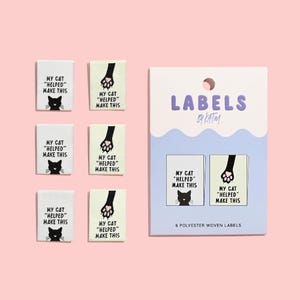 May include: Six rectangular polyester woven labels featuring black text that reads MY CAT HELPED MAKE THIS. Three labels show a black cat face, and three show a black cat paw. The labels are displayed loose and on a branded white and blue card.