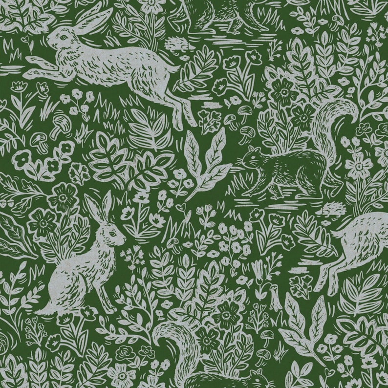 Op de afbeelding: Een groene achtergrond met een wit herhalend patroon van konijnen, eekhoorns en bloemen. Het patroon doet denken aan een houtsnede.