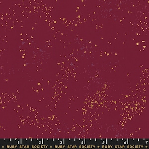 May include: A deep red fabric with a scattered pattern of small gold and purple dots.