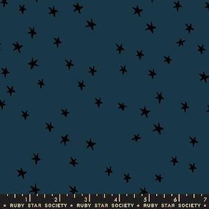 Op de afbeelding: Een donkerblauwe stof met een herhalend patroon van zwarte sterren. De stof heeft een liniaal met de tekst "RUBY STAR SOCIETY" erop gedrukt.