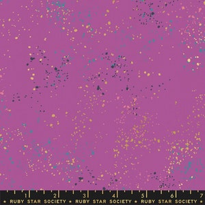 May include: A vibrant purple fabric with a speckled design. The fabric features a pattern of small, irregular dots in shades of gold, teal, and navy blue, creating a textured effect. The words "RUBY STAR SOCIETY" are printed at the bottom.