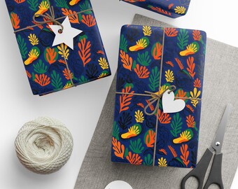 May include: Gift-wrapped presents with a navy blue floral pattern featuring orange, yellow, and green shapes. Each gift is tied with twine and a white tag. A ball of twine, scissors, and blank tags are also visible.