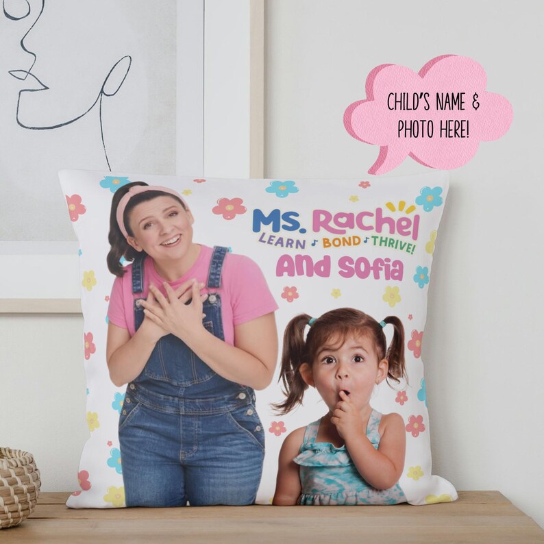 May include: White pillow with a colorful floral pattern. The pillow features a photo of two women, one with a pink shirt and blue overalls, the other with a blue and green dress. The text on the pillow reads "Ms. Rachel Learn Bond Thrive! And Sofia".