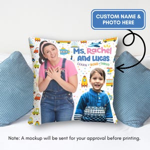 May include: A white pillow with a colorful design featuring a woman and a child. The text on the pillow reads "Ms. Rachel and Lucas. Learn Bond Thrive!"