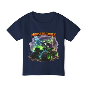 May include: Navy blue t-shirt featuring a green and purple monster truck design. The graphic includes lightning bolts, skulls, and the words "MONSTER TRUCK" in orange. The truck has large green wheels and is set against a cloudy background.