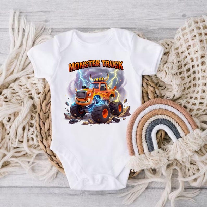 Puede incluir: Body de beb&eacute; blanco con un gr&aacute;fico colorido de un cami&oacute;n monstruo naranja con llamas, rayos y el texto "MONSTER TRUCK". El dise&ntilde;o est&aacute; sobre un fondo de cielo tormentoso.