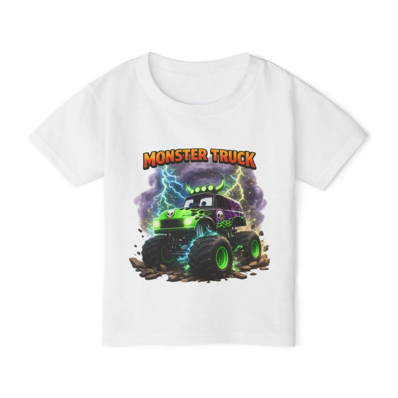 May include: White t-shirt featuring a colorful graphic of a monster truck with a skull design, lightning bolts, and the words "Monster Truck" in orange and yellow. The truck is green and purple.