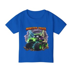 May include: A blue t-shirt featuring a green and purple monster truck design with the text "MONSTER TRUCK". The graphic includes lightning bolts and a skull design on the truck.