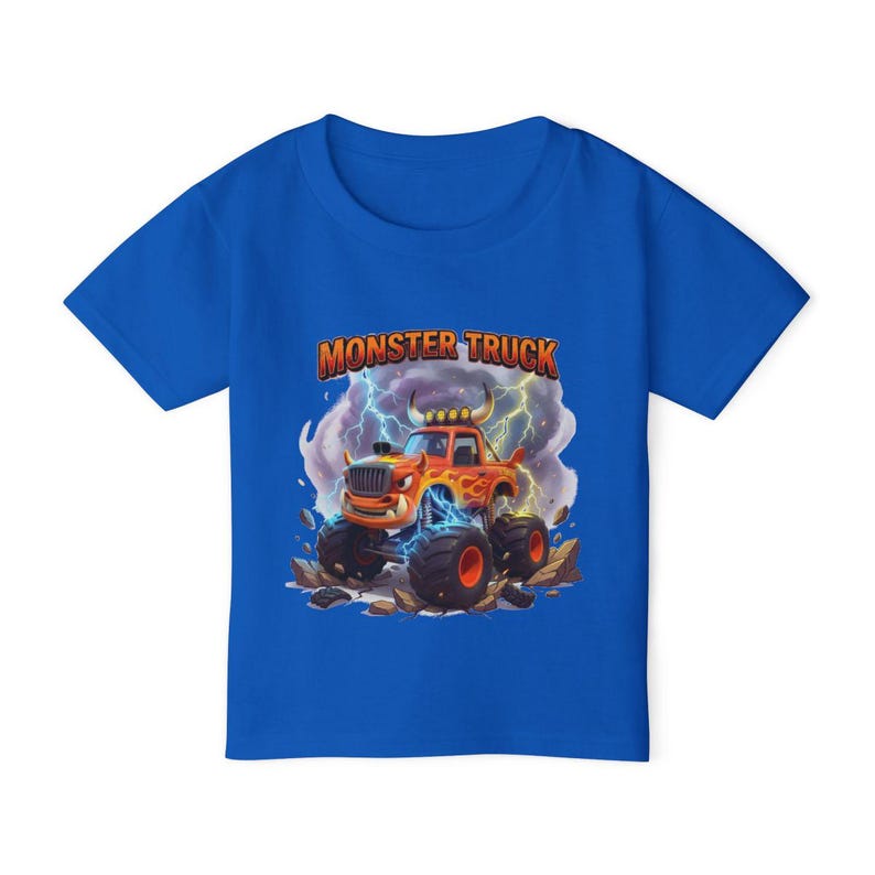 Puede incluir: Una camiseta azul con un gr&aacute;fico de un cami&oacute;n monstruo naranja con llamas, neum&aacute;ticos grandes y el texto "MONSTER TRUCK". El dise&ntilde;o incluye rayos y un suelo rocoso.
