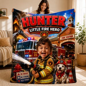 Op de afbeelding: Een gepersonaliseerde fleece deken met een brandweerkazerne, een rode brandweerwagen, een kind in brandweerkleding met een slang en een dalmatiër puppy. De tekst luidt HUNTER LITTLE FIRE HERO en BE BRAVE BE STRONG HELP OTHERS.