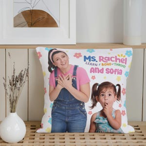 May include: White pillow with a colorful floral pattern. The pillow features a photo of Ms. Rachel and Sofia, with the text "Ms. Rachel Learn, Bond, Thrive! And Sofia".