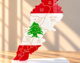 Könnte beinhalten: Eine dekorative Landkarte des Libanon in Landesform, die die Nationalfarben Rot, Weiß und Grün mit einer zentralen Zeder zeigt. Die Karte ist in Regionen unterteilt, die auf Arabisch und Englisch beschriftet sind, und steht auf einem weißen Sockel.