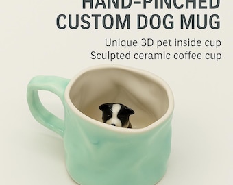 May include: A hand-pinched, custom dog mug in a light teal color. The mug features a unique 3D sculpted ceramic dog inside the cup. The mug has a handle and is designed for coffee.