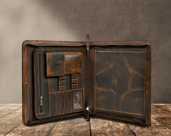 May include: A dark brown leather portfolio case with a full zipper closure. The interior features a zippered pocket, a flap pocket, multiple card slots, a clear identification window, and several pen loops, with a large open sleeve on the right side.