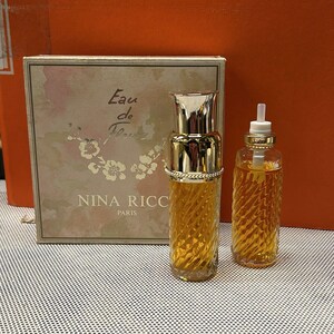 Könnte beinhalten: Ein Set aus zwei Parfümflacons mit goldener Kappe und einem strukturierten Glasdesign. Die Flacons enthalten eine hellgelbe Flüssigkeit. Die Schachtel ist weiß mit rosa Blumen und dem Text "Eau de Fleurs Nina Ricci Paris".