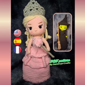 May include: A crochet doll with blonde hair, a silver crown, and a layered pink dress, holding a wand. An inset shows a green-skinned witch doll in a black dress and hat holding a broom. Text reads PDF pattern by Jaenerys Crafts.