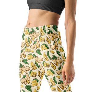 May include: Cream-colored joggers with a repeating pattern of ginger root, slices, and green leaves. The design features various sizes and shapes of ginger, creating a botanical theme. The joggers are made of a soft, comfortable material.