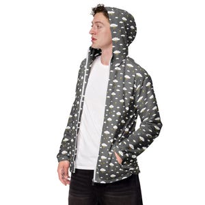 May include: A gray zip-up hooded jacket with a white cloud and lightning bolt pattern. The jacket has a white zipper and a hood. The person in the image is wearing a white t-shirt underneath.