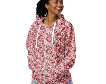 May include: A pink zip-up hoodie with a floral print. The hoodie has a white zipper and a white drawstring hood.