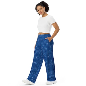 May include: Blue wide-leg pants with a repeating pattern of numbers and symbols. The pants have pockets and are worn with a white crop top and white sneakers. The pants are made of a soft, comfortable material.