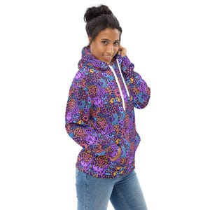 May include: A purple hoodie with a colorful pattern of zodiac signs and symbols. The hoodie has a white drawstring and a kangaroo pocket.