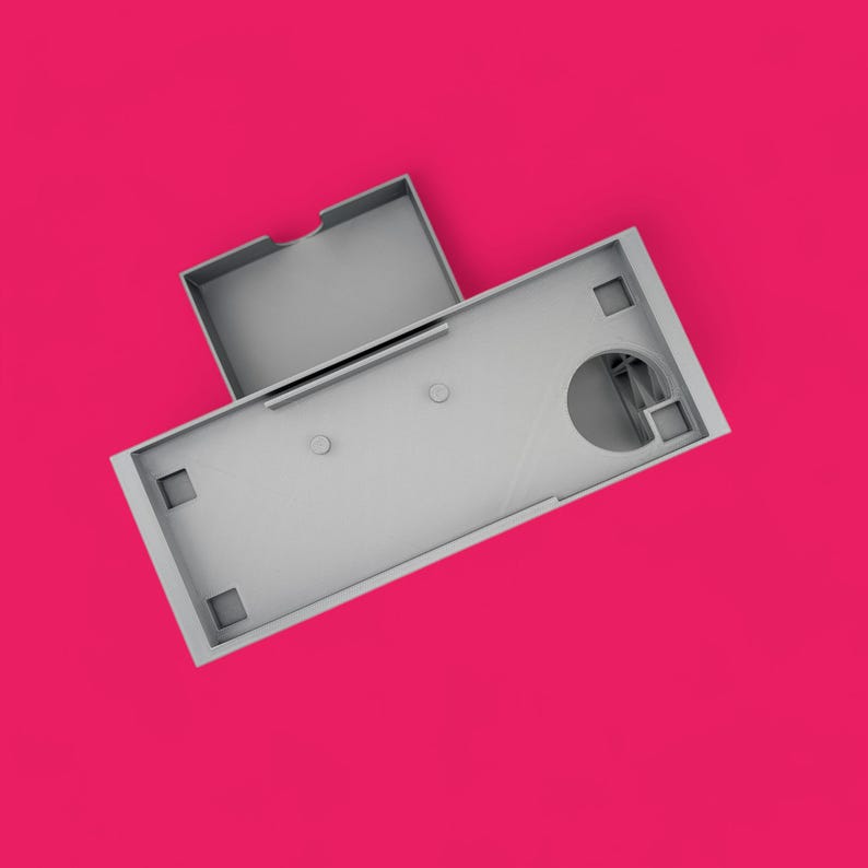 May include: A gray model of a building with a flat roof and a circular opening. The building has a smaller rectangular addition on top.