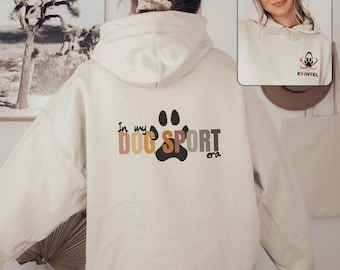 May include: A cream coloured hoodie with a black paw print and the text "In my dog sport era" printed on the back. The front of the hoodie has a small logo with the text "K9 INTEL".