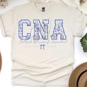 May include: A beige t-shirt with a blue floral design that spells out "CNA" with the text "Certified Nursing Assistant" and "DIGITAL DESIGNER" below.
