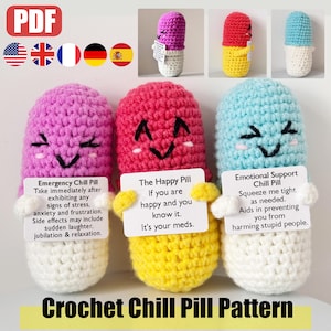 Könnte beinhalten: Drei gehäkelte Pillen-förmige Plüschtiere mit fröhlichen Gesichtern und verschiedenen Körperfarben. Jedes Plüschtier hält eine Karte mit einer anderen Botschaft: "Emergency Chill Pill", "The Happy Pill" und "Emotional Support Chill Pill".