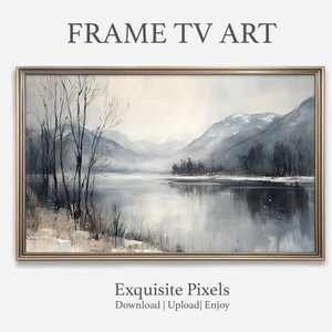 May include: A framed landscape painting of a serene lake scene with mountains in the background. The artwork features a muted color palette of blues, grays, and whites, with bare trees in the foreground. The text "FRAME TV ART" and "Exquisite Pixels" are visible.
