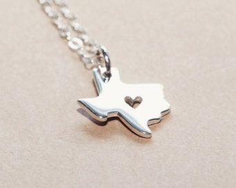 May include: A silver necklace with a pendant shaped like the state of Texas. The pendant has a small heart cut out of the center.