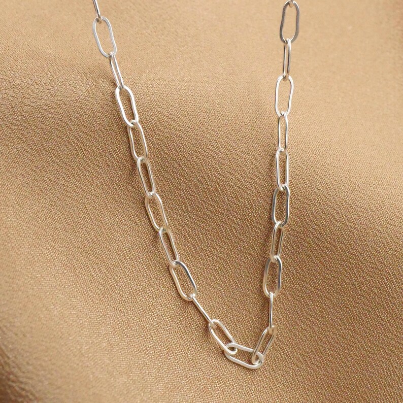 May include: A silver chain necklace with oval links.