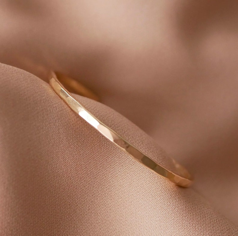 May include: A simple gold hammered band ring. The ring is smooth and has a subtle hammered texture.
