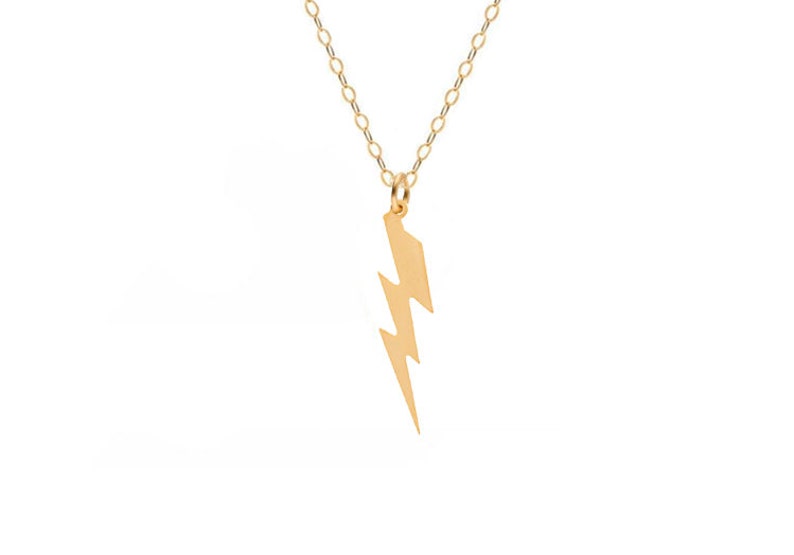 May include: A gold chain necklace with a lightning bolt pendant.