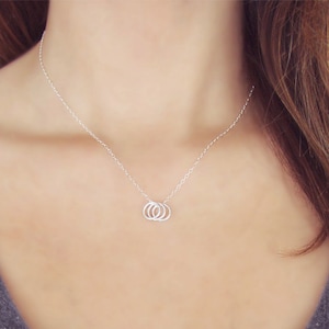 May include: A silver necklace with three interlocking rings as a pendant.