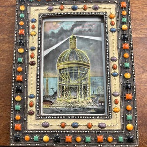 Grabado antiguo de la Torre Globe de Coney Island, propuesta por Samuel Friede en 1906, en un marco de fotos multicolor adornado. Historia incluida en el reverso.