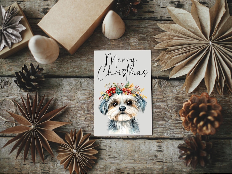 K&ouml;nnte beinhalten: Eine Weihnachtskarte mit einer Aquarell-Illustration eines kleinen Hundes, der einen Kranz aus Blumen und Beeren tr&auml;gt. Die Karte tr&auml;gt den Text "Merry Christmas" in schwarzen Buchstaben.
