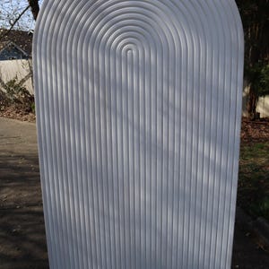 May include: White arched room divider with a series of curved lines creating a geometric pattern.