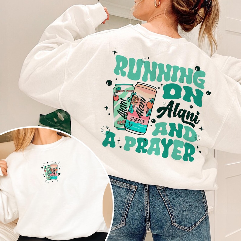 May include: White sweatshirt with the text "RUNNING ON Alani AND A: PRAYER" in teal and black. The design includes two beverage cans with the Alani Energy logo. A smaller version of the design is on the front.