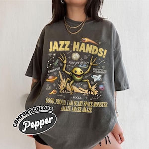May include: Dark grey t-shirt with the text "JAZZ HANDS!" and a cartoon space monster. The shirt also features the text "SARCASM", "FIST MY BUMP!", "WHY STUPID QUESTION", and "GOOD, PROUD, I AM SCARY SPACE MONSTER".