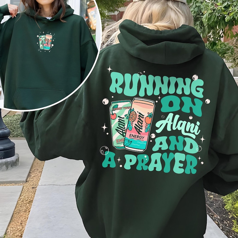 May include: Dark green hoodie with the text "RUNNING ON Alani AND A PRAYER" in teal. The design includes two Alani Nu energy drink cans. A smaller version of the design is on the front. The hoodie has a hood and a front pocket.