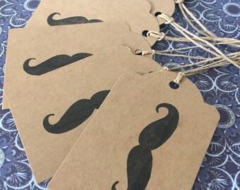 May include: Set of six brown kraft paper gift tags with black printed mustache designs. Each tag has a hole punched at the top and comes with a twine string.