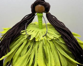 May include: A handmade doll with a wooden bead head, brown yarn hair, and a lime green fabric dress. The doll's dress is made of layered fabric petals. A wire frame is attached to the doll's head.