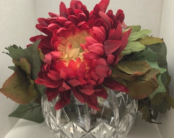 May include: A red and yellow flower arrangement in a clear crystal vase with a diamond pattern.