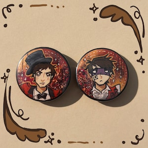 May include: Two round buttons with illustrations of male figures. One figure wears a top hat and a red jacket, the other has a purple mask and a red vest. Both have a dark background with floral and star details.