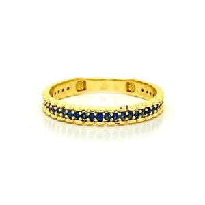 May include: A gold band ring with a row of blue sapphires.