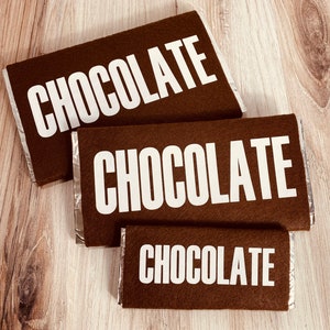 May include: Three brown felt chocolate bar wrappers with the word "CHOCOLATE" printed in white on each.