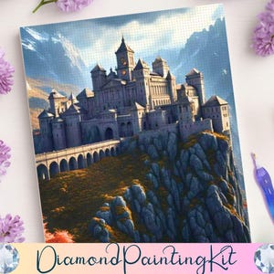 May include: A diamond painting kit featuring a detailed illustration of a castle atop a rocky cliff, with a bridge and towers. The artwork is set against a backdrop of mountains and a blue sky. The words "Diamond Painting Kit" are at the bottom.